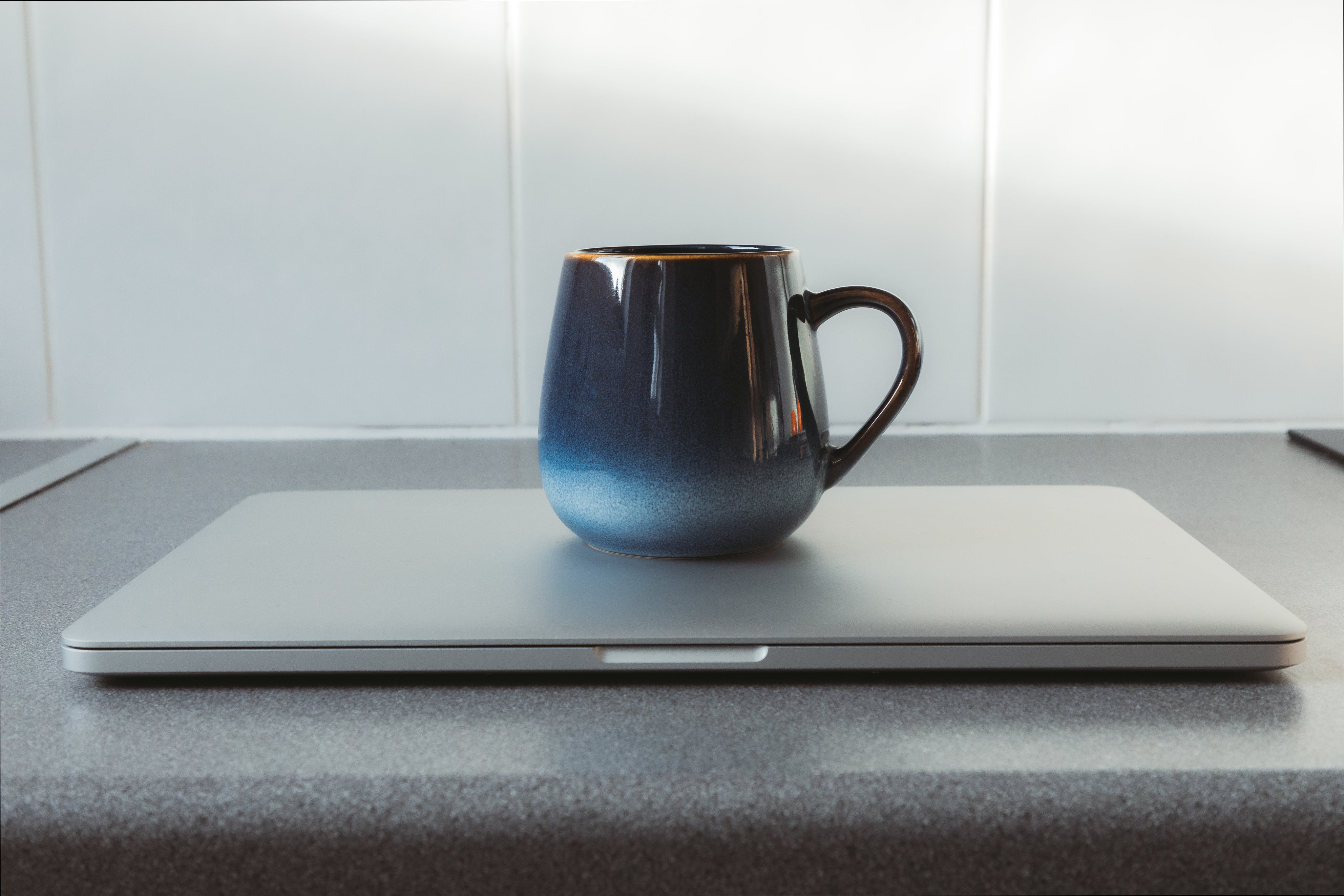 blue-mug-sits-on-a-closed-silver-laptop.jpg